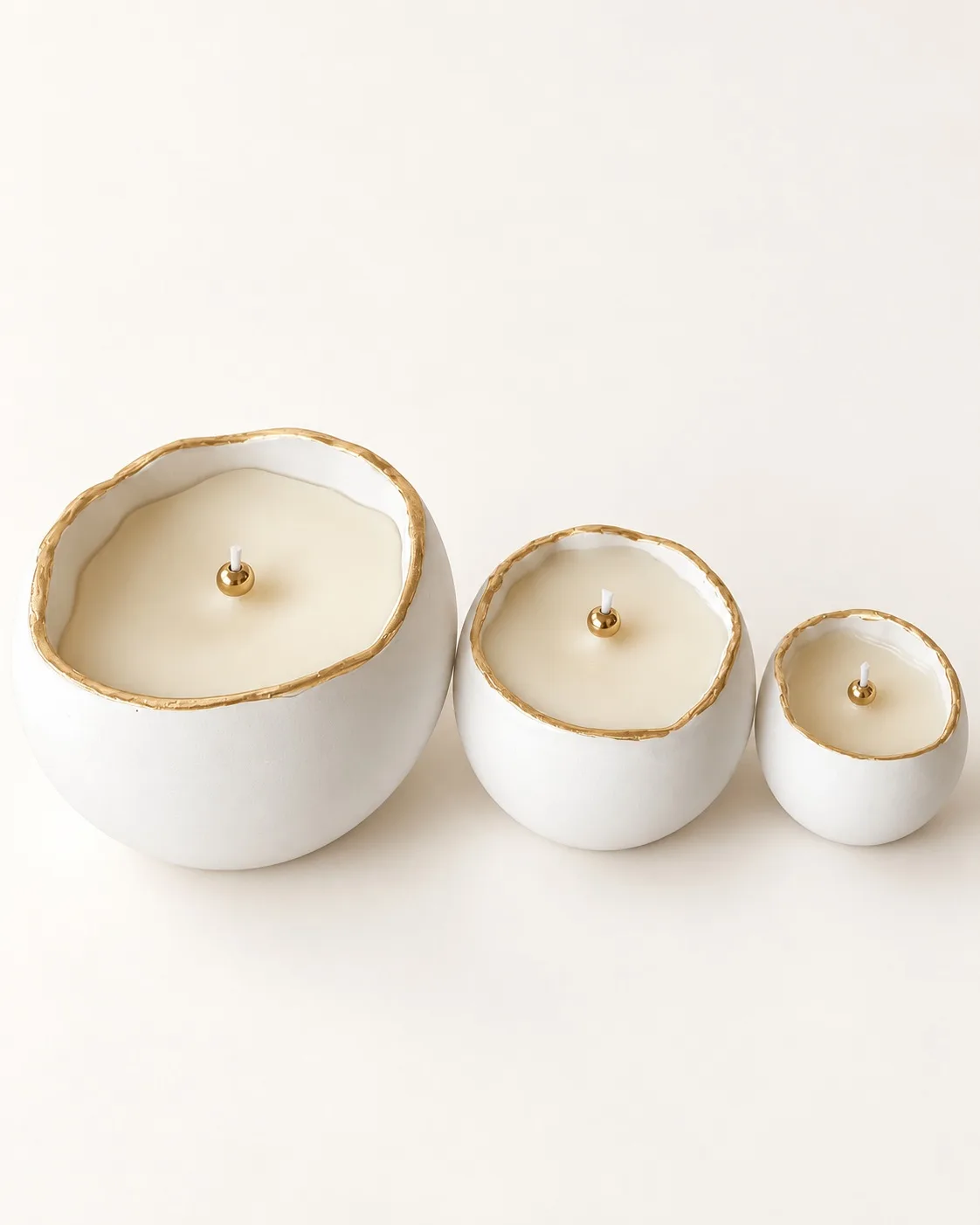 Três velas aromatizadas de tamanhos diferentes com rebordos dourados