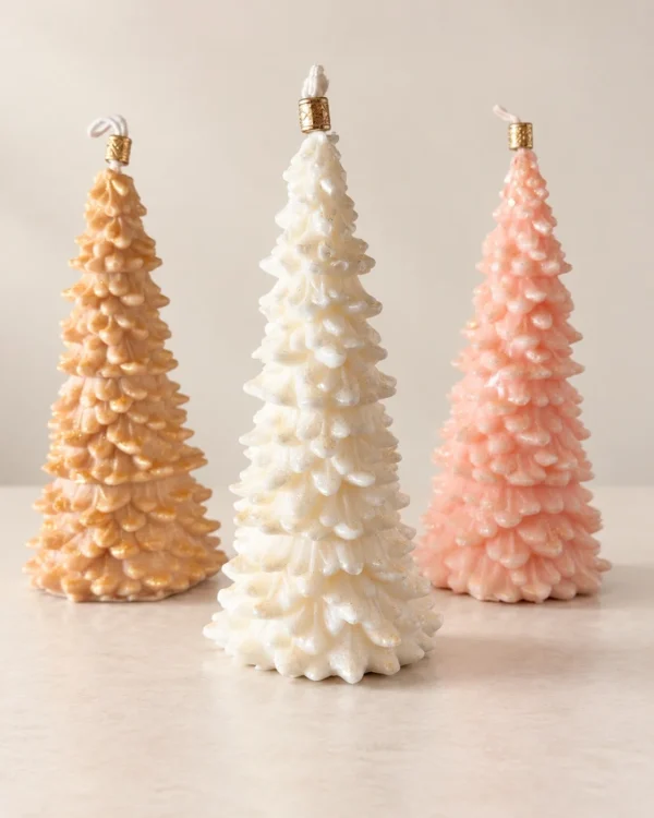 Três velas em forma de árvore de Natal em pêssego, marfim e rosa.