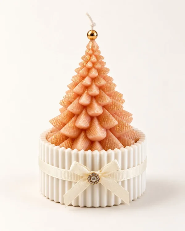 Vela em forma de árvore de Natal cor de pêssego num copo de gesso com laço