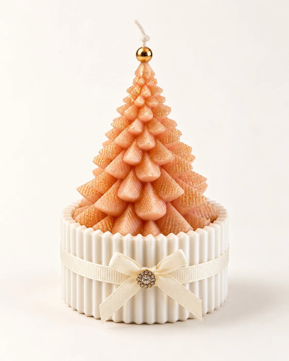 Vela em forma de árvore de Natal cor de pêssego num copo de gesso com laço